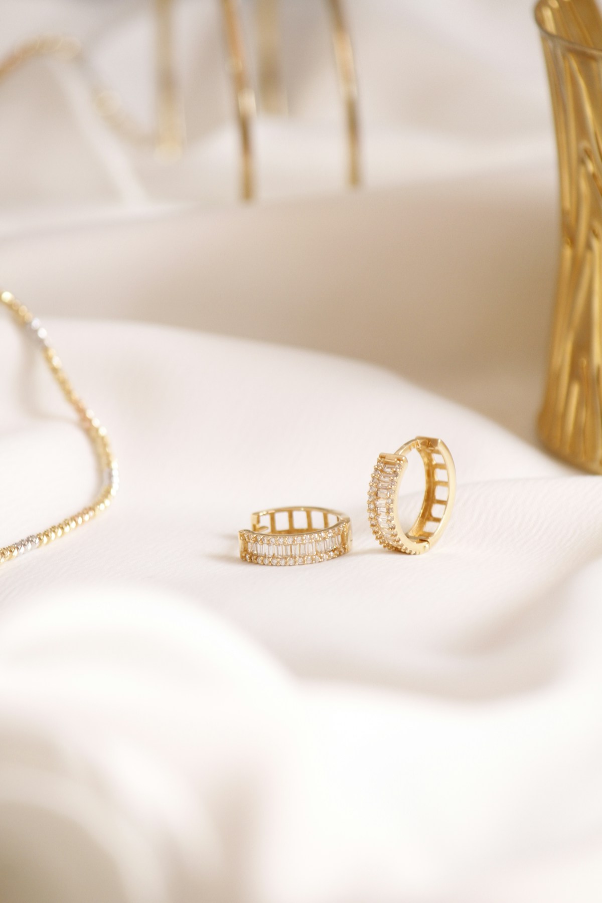 A pair of gold huggie earrings set with baguette diamonds