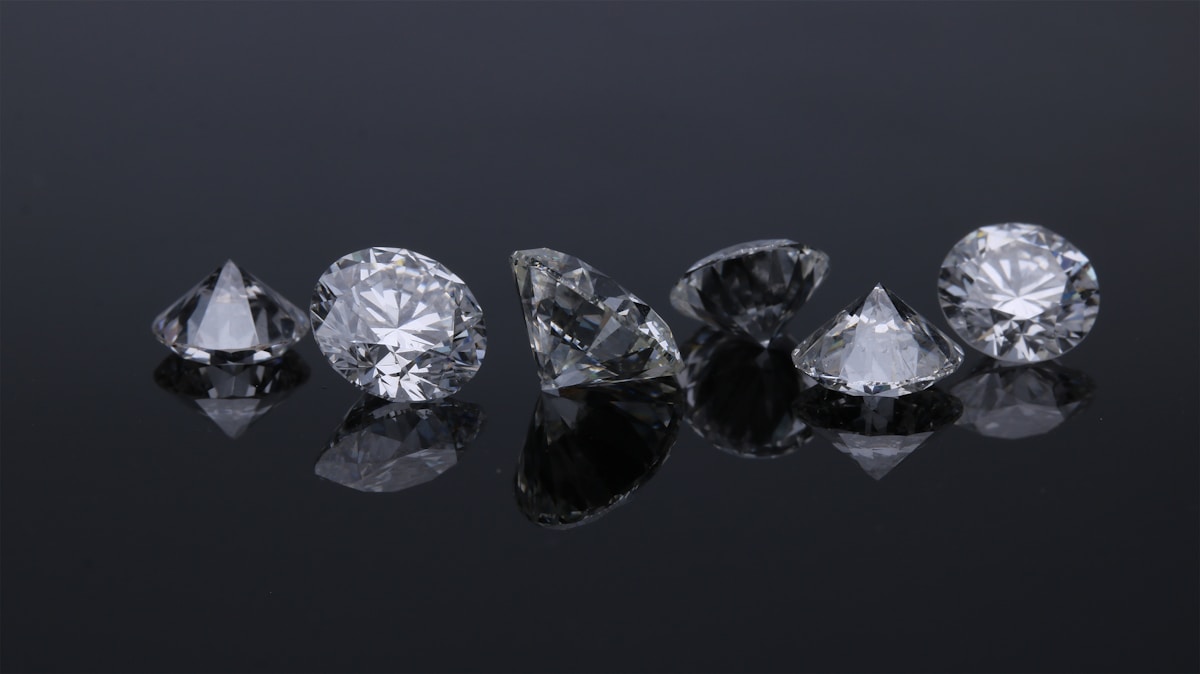 Several loose faceted diamonds arranged on a dark reflective surface
