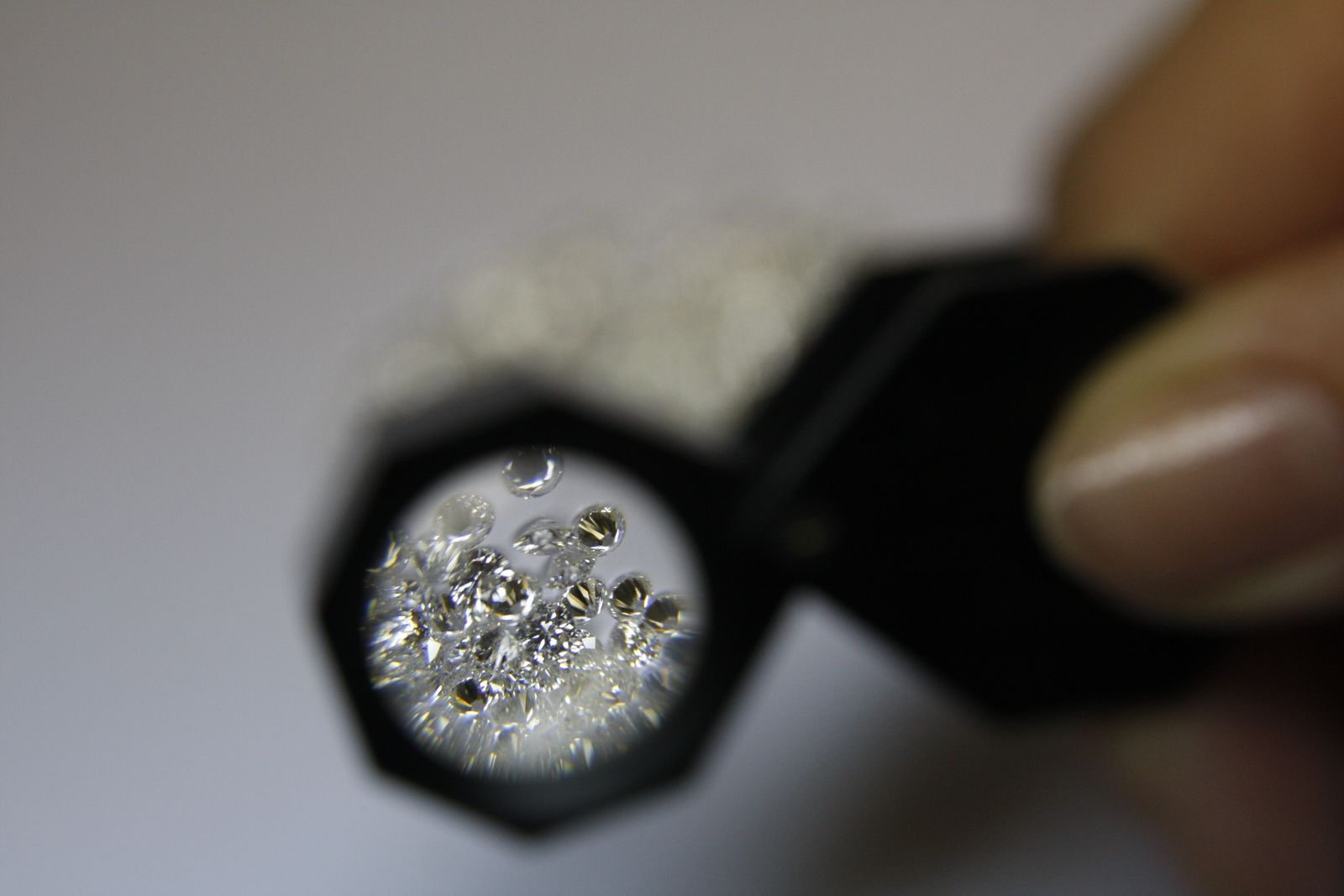 Loose diamonds examined closely through a jeweler's loupe