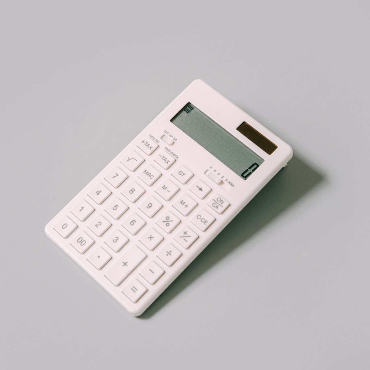 A minimalist white calculator with visible tax buttons on a gray background