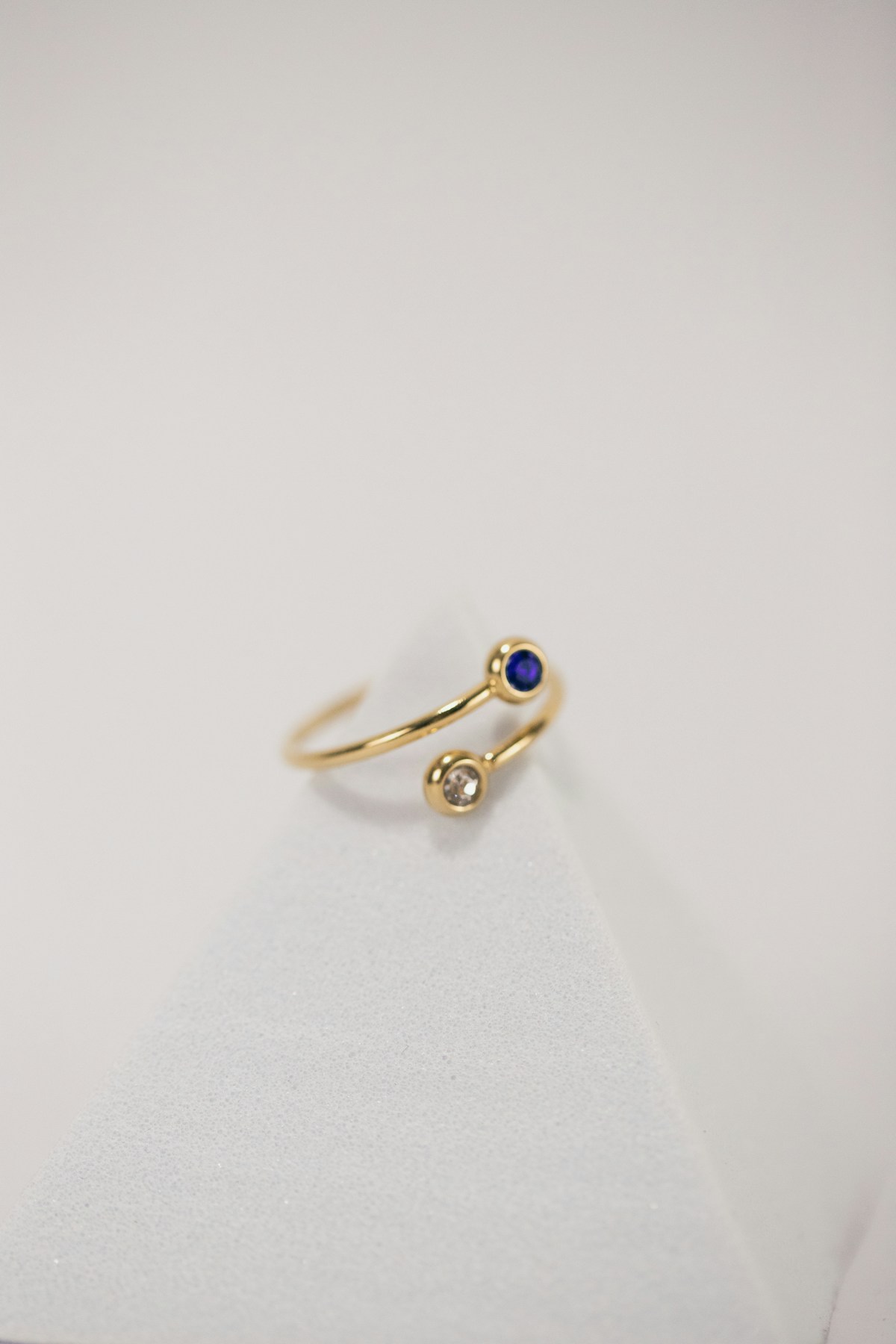 A gold bypass ring set with a blue sapphire and a diamond side by side